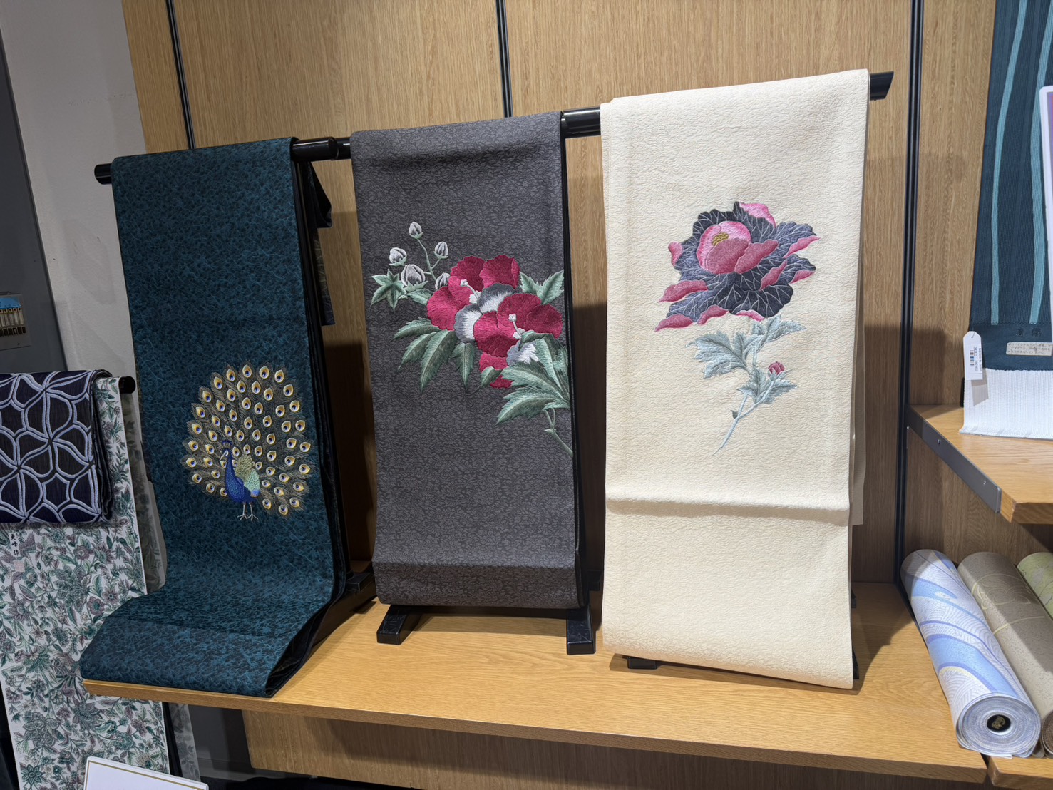 孔雀や花の柄を配した帯の店内展示